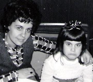 1970s mom and 5 year old daughter in party clothes, frowning.